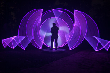 One person standing alone against a Colourful circle light painting as the backdrop