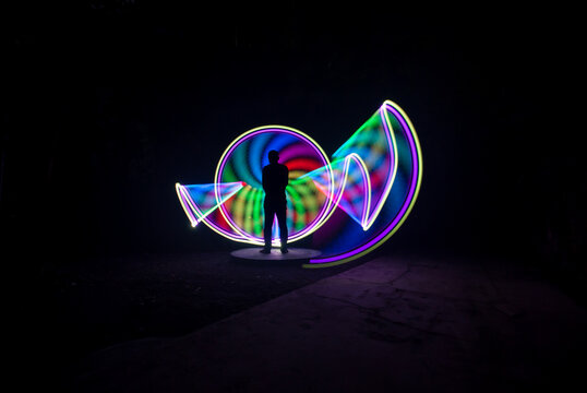 One person standing alone against a Colourful circle light painting as the backdrop