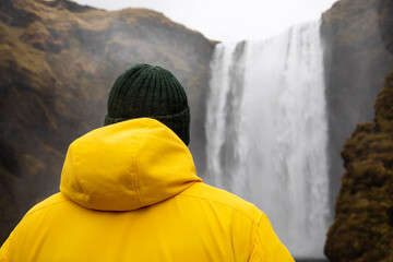 Hiker looking at water fall in yellow jacket