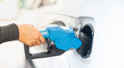 Female worker hand holding nozzle fuel fill oil into car tank at pump gas station, For the concept transportation power business technology concept.