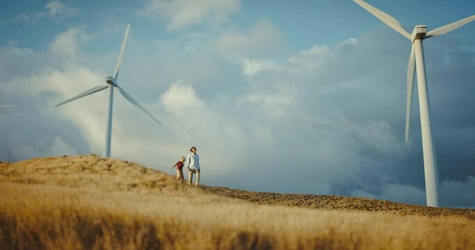 Happy father and son walking under windmills, family lifestyle, spending quality time together, clean energy future, environment and sustainability concept