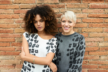 Beautiful smiling friends in animalistic outfit on brickwall
