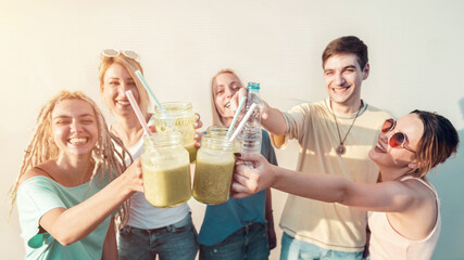 Group of young friends celebratory toast with fresh organic smoothie drinks, healthy drinks and...