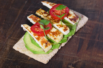 Crispy bread with avocado, halloumi cheese, tomato, and coriander