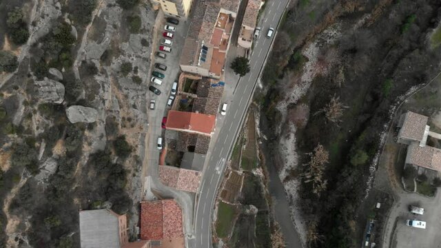 Top down aerial view of cars driving on the road through beautiful old village on the hill in Margalef, Tarragona. Aerial view traffic through small old village in Catalonia, Spain