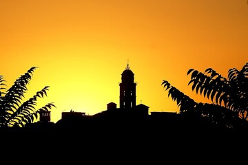 Silhouette of a bell at colorful sunset and tree leaves