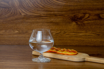 glass with white tequila and spicy orange slices on elegant wooden background. mezcal