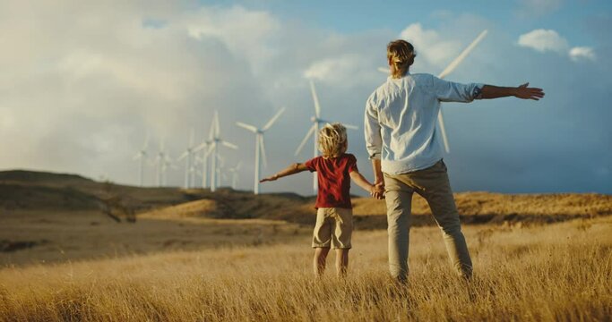 Father and son with windmills at sunset, dreaming of a clean and sustainable future for generations to come, heart warming uplifting picture of clean energy for the environment