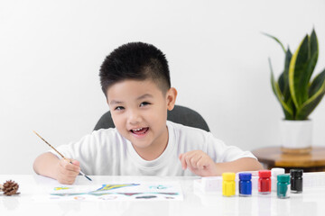 Happy little Asian kid at the table draw with water color Learning and education of kid.