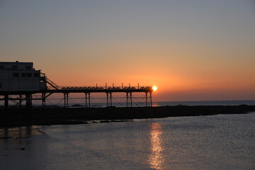 Fototapeta na wymiar a view of the sun setting behind Aberystwyth pier 