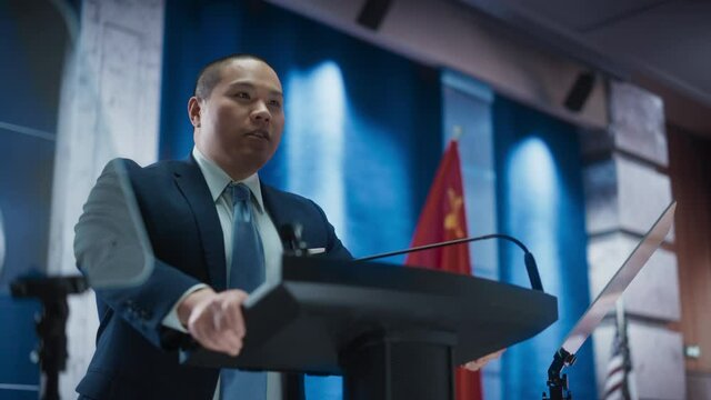 Portrait of Chinese Organization Representative Speaking at Press Conference. Minister Delivering a Speech at Congress. Backdrop with United States of America and People's Republic of China Flags.