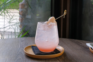 Cold refreshing  lychee soda in a glass on the wooden table, fruits Italian soda