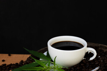 Obraz na płótnie Canvas Black coffee cup with saucer and cannabis leaves Placed on a black background
