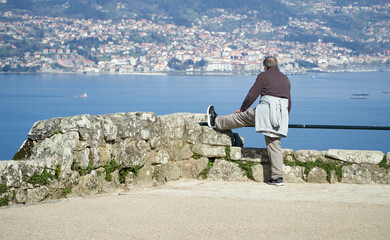 Senior citizen in sportswear doing sports outdoors. Abandoned elderly man stretching in a viewpoint in Vigo. old man in viewpoint doing sports