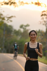 Portrait of sporty young woman jogging at the park in evening.
