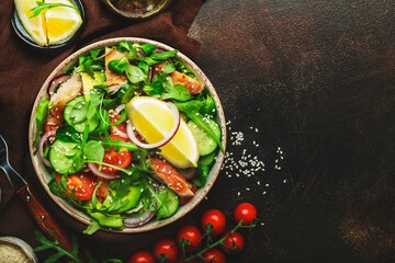 Fresh salad with grilled chicken, cherry tomatoes, arugula, red onion, avocado, sesame seeds and lemon oil dressing. Healthy food concept. Top view. Copy space