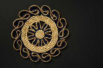Handmade round wicker placemat on black background with copy space