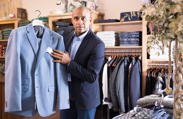 Portrait of confident salesman demonstrating suits in apparel shop