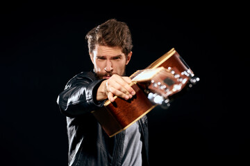 A man with a guitar in his hands leather jacket music performance rock star modern style dark background