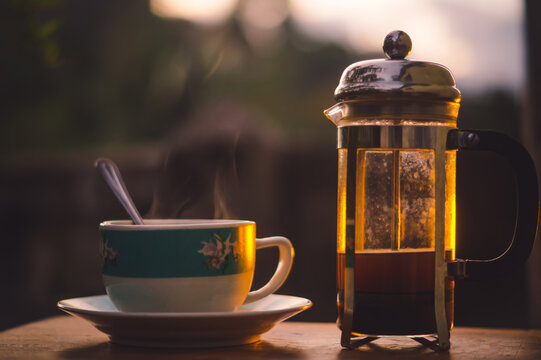 Taza de caf&eacute; caliente, preparada en cafetera francesa o prensa francesa al atardecer, con caf&eacute; reci&eacute;n molido 