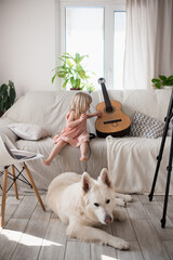 Little girl, child is engaged in guitar practice, home interior, child development at home, hobbies. High quality photo