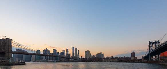 Naklejka premium Wide panorama image of Manhattan Skyscrapers and Brooklyn bridge at dusk in New York, USA