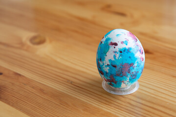 Obraz na płótnie Canvas One Easter egg interspersed on wooden background.
