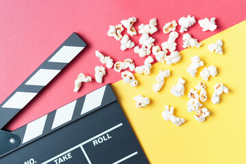 The clapperboard and popcorn on yellow and red background top view.