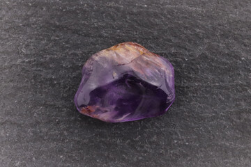 Rutilated amethyst jewel stone texture on black stone background. Macro closeup.