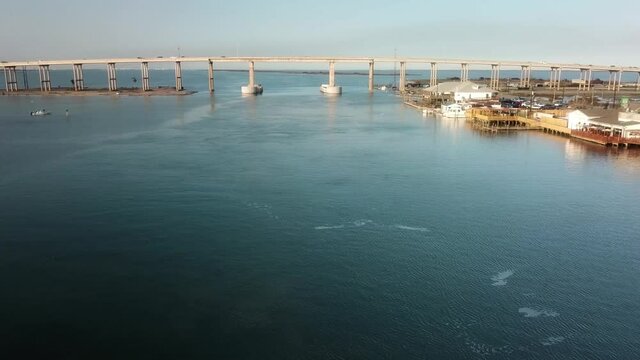 Aerial drone view of shipping channel of the Gulf Intercoastal Waterway in northern Laguna Madre; flying along shore line with a marina and other buildings; North Padre Island, Corpus Christi Texas