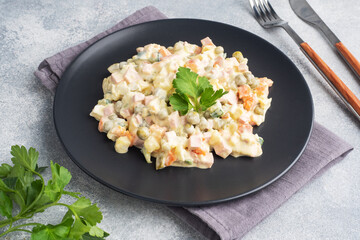 Olivier salad with mayonnaise on a plate. Russian is a traditional festive dish.