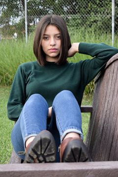 Retrato de una Mujer Guatemalteca joven sentada en una banca de madera, cabello liso y corto.