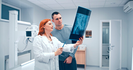 Mature doctor showing X ray scan to patient