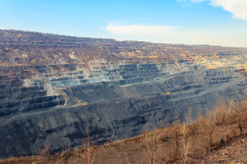 Huge iron ore quarry with working dump trucks and excavators