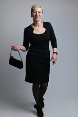Full length portrait of caucasian woman with handbag on gray background