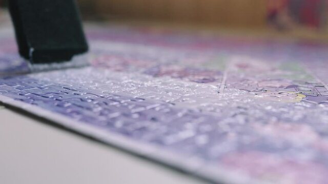 The hobbyist paints a puzzle with mod podge glue.