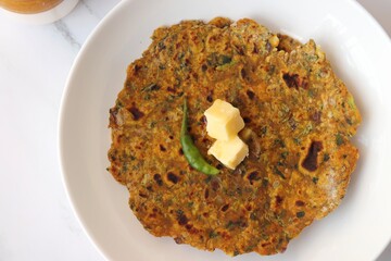 Radish or Mooli masala Paratha served on a white plate with butter cubes. Served with curd, pickle, and green chili. copy space. Muli ke parathe. Radish masala roti.