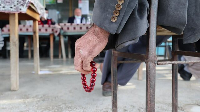 Close up of an old man's hand fingering beautiful red rosary