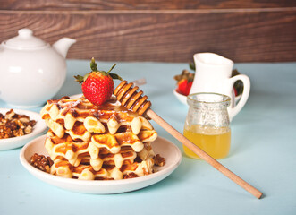 Freshly homemade baked waffles with strawberries and honey.