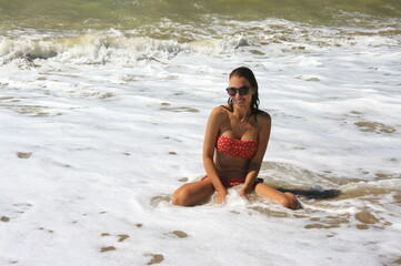 Young woman on sand by sea wave