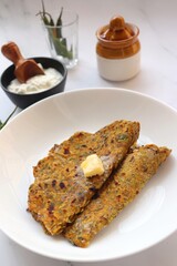 Radish or Mooli masala Paratha served on a white plate with butter cubes. Served with curd, pickle, and green chili. copy space. Muli ke parathe. Radish masala roti.