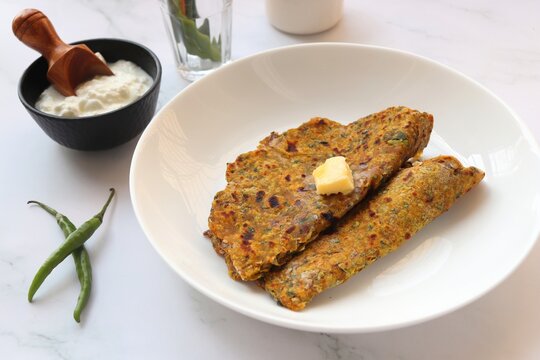 Radish or Mooli masala Paratha served on a white plate with butter cubes. Served with curd, pickle, and green chili. copy space. Muli ke parathe. Radish masala roti.