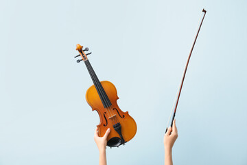 Woman holding violin and bow on color background
