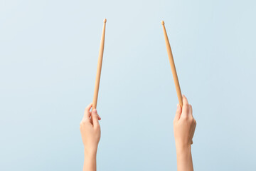 Woman holding wooden drumsticks on color background
