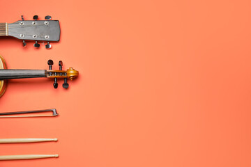 Acoustic guitar, violin, bow and drumsticks on color background