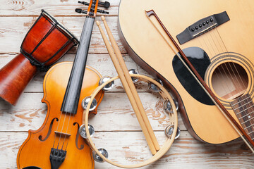 Different musical instruments on light wooden background, closeup - obrazy, fototapety, plakaty