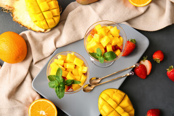 Glass bowls with tropical fruit salad on dark background