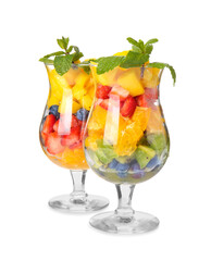 Glasses with tropical fruit salad on white background