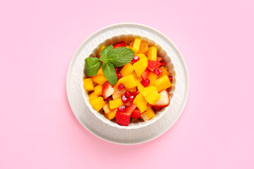 Bowl with tropical fruit salad on color background