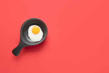 Frying pan with tasty egg on color background